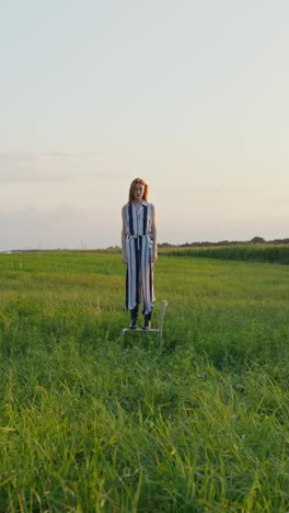 woman in striped jumpsuit on a chair in a field at sunset