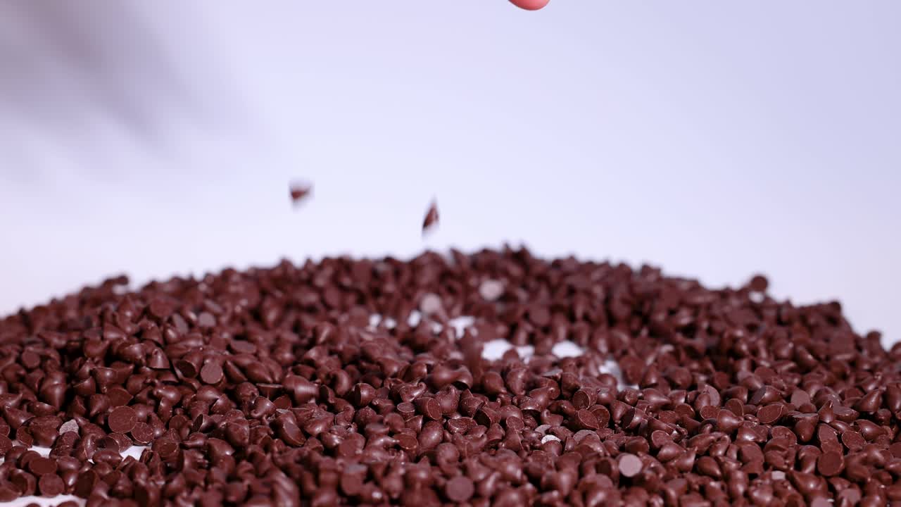 Hand sifting through chocolate chips on surface