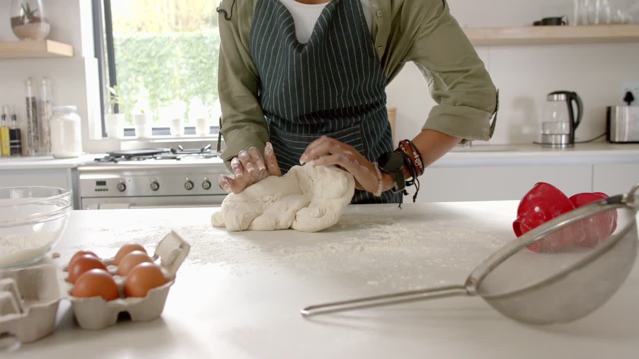 African American young woman kneading dough in kitchen