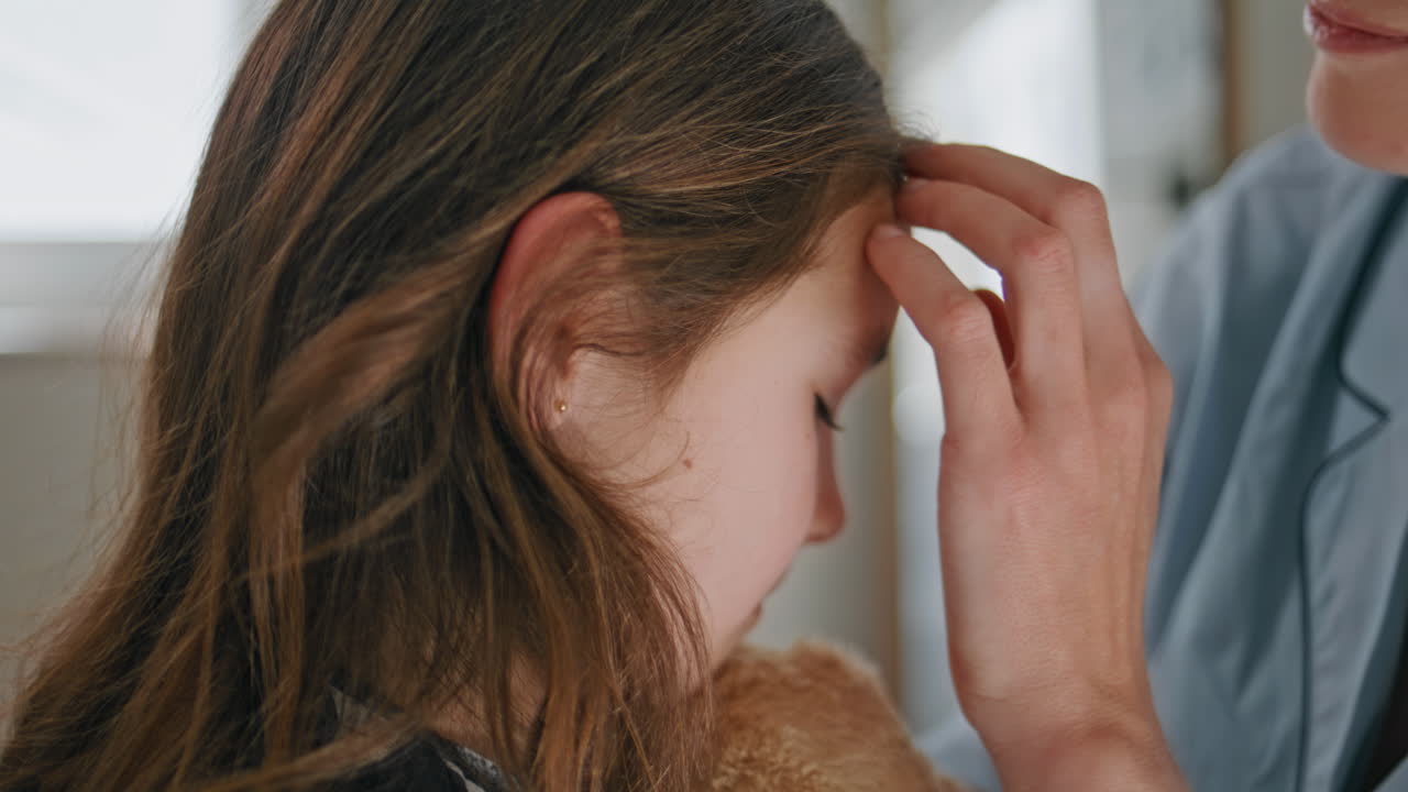 Tender mother touching daughter hair at home closeup. Woman kissing toddler