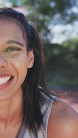 vertical video half portrait of female biracial basketball player on sunny court, in slow motion