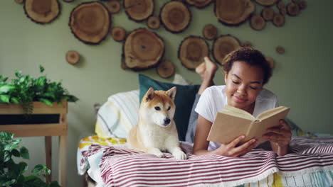 teenager reading a book with dog on bed