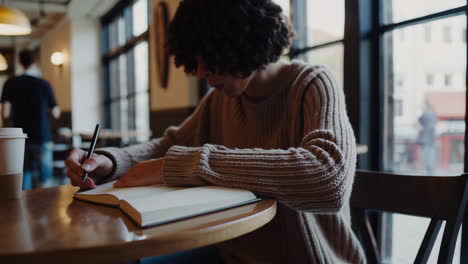 woman writing in a cafe