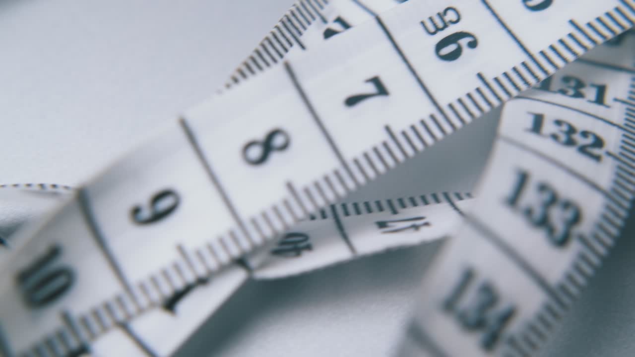 부드러운 플라스틱 테이프 측정은 밝은 회색 표면 클로즈업에 있습니다