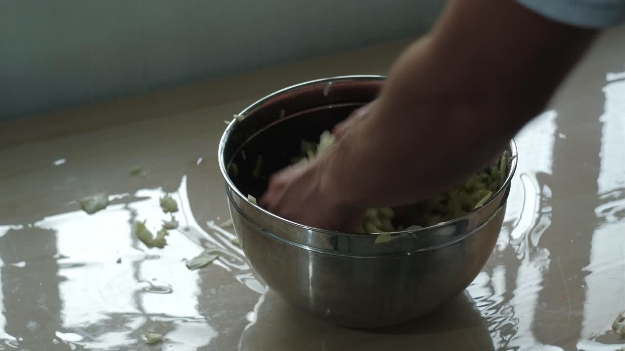Hand Mixing The Thinly Sliced Cabbage In a Stainless Bowl. - closeup shot