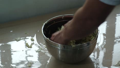 hand mixing the thinly sliced cabbage in a stainless bowl. - closeup shot