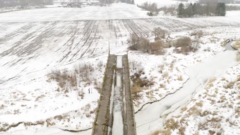 aerial view of abandoned bridge and agricultural field during winter