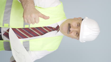 Vertical-video-of-Old-engineer-looking-at-camera-and-making-positive-gesture.