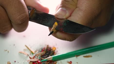 Footage-of-hands-slowly-sharpening-a-pencil-and-some-coloured-pencils-with-a-sharp-knife