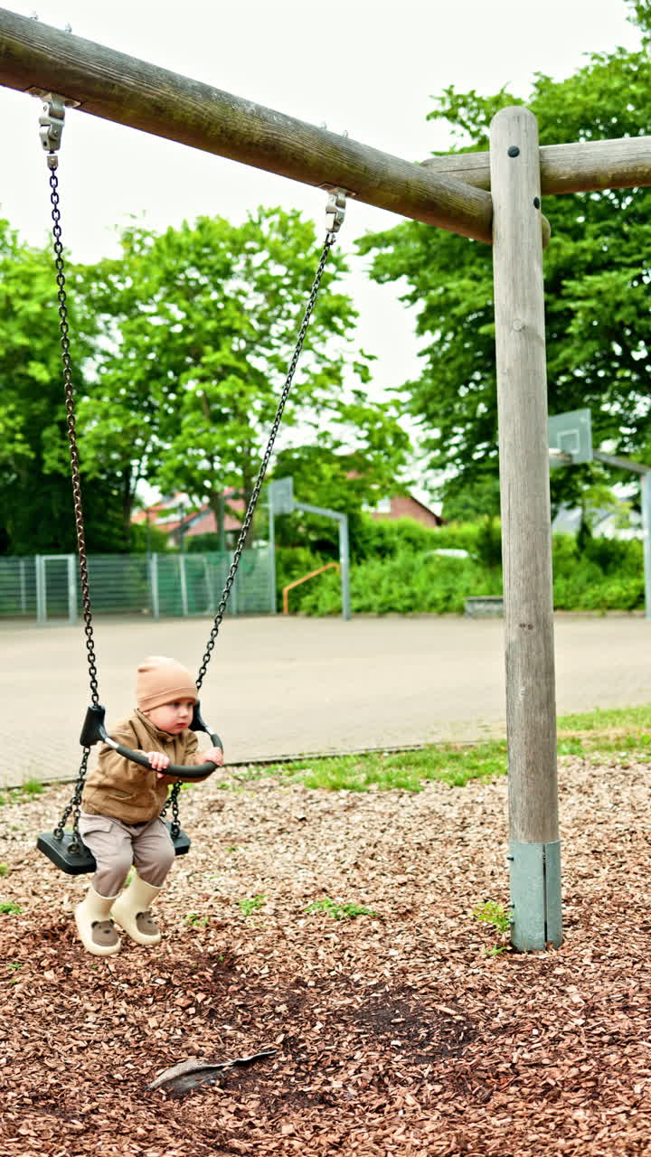 Un bambino allegro si dondola sull'altalena per strada. Il bambino si dondola sull'altalena al parco giochi. Divertimento per i bambini in un parco giochi cittadino. Il bambino gioca per strada. Sviluppo del bambino.