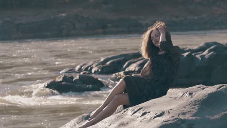 Chica-Elegante-Con-Vestido-Corto-Sentada-Sobre-Enormes-Rocas-En-Cámara-Lenta