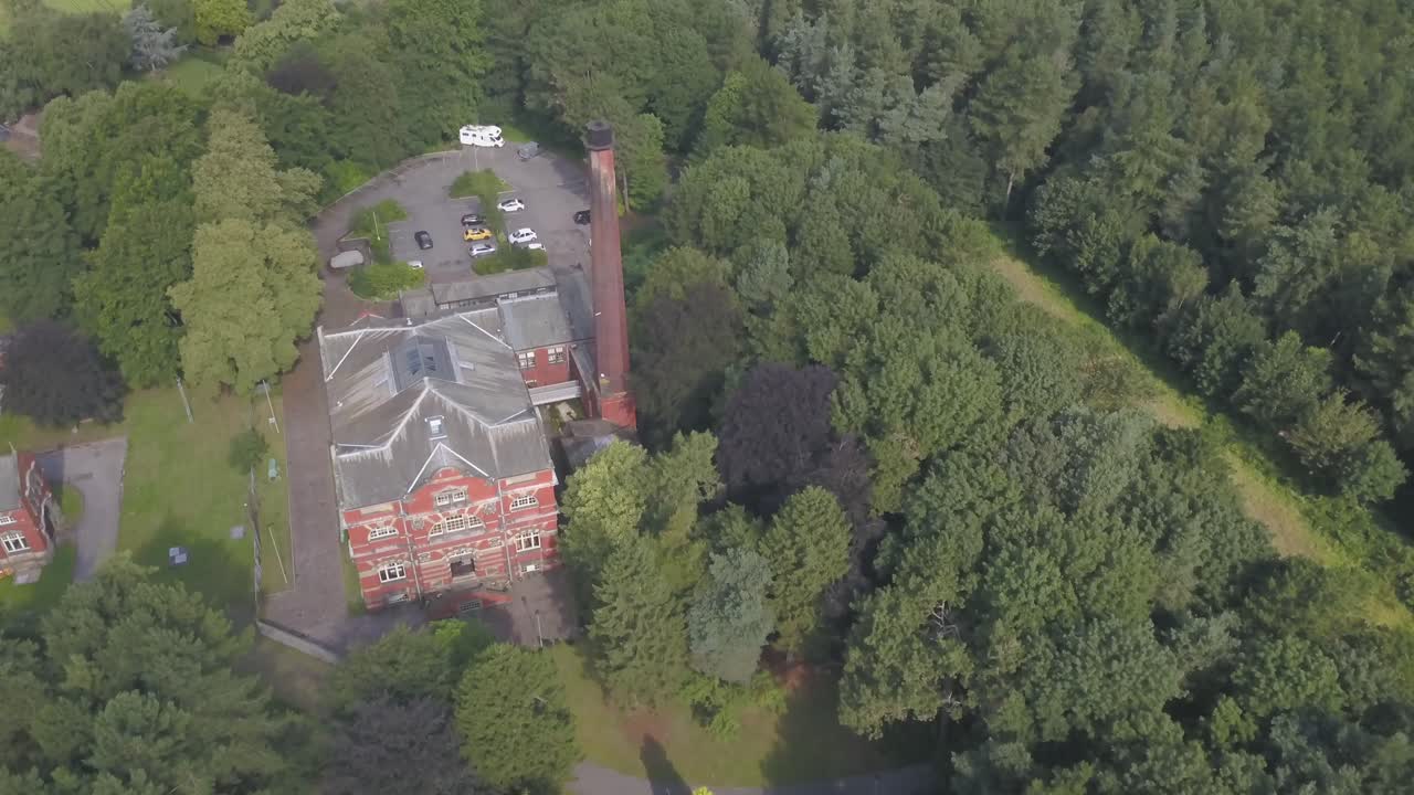 Push out 4k drone footage of a brick building in the middle of a forest