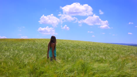 a pretty young girl walks in a field with her hair blowing