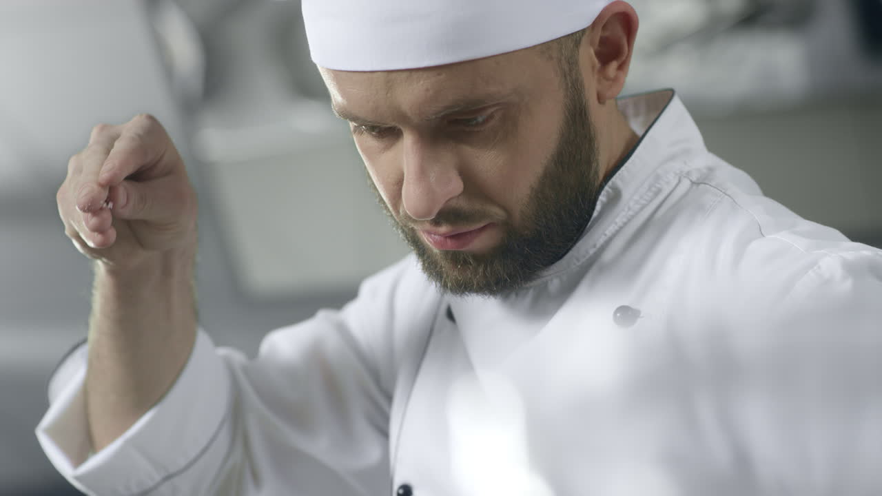 Chef che sala il cibo in una cucina professionale. Cuoco serio che prepara il cibo.