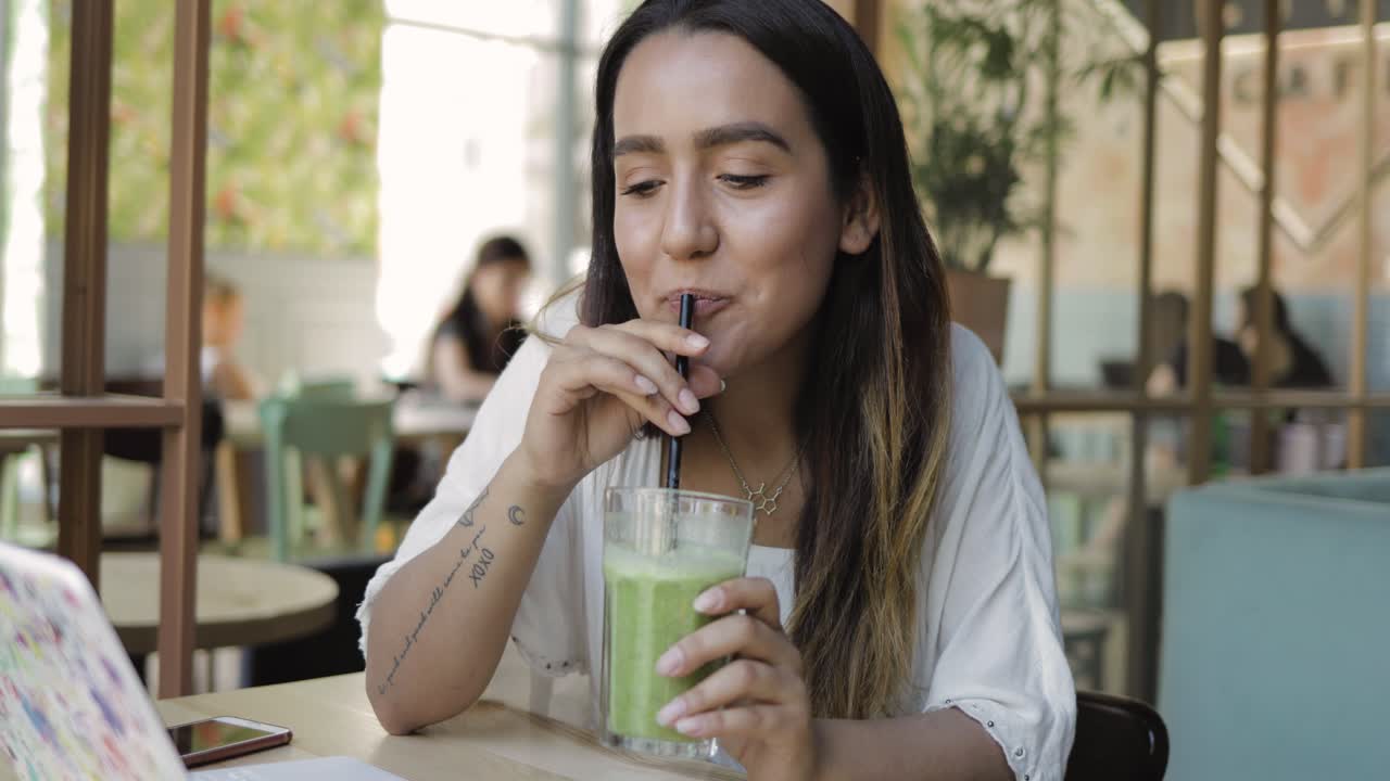 Giovane donna che sorseggia un frullato verde salutare