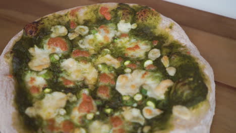 slow motion pan forward from a blurry background to in focus of a delicious homemade italian pizza with a sourdough crust ready to be sliced and enjoyed by the whole family