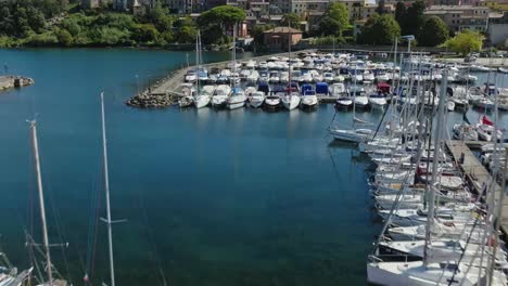 Aerial-over-the-marina-and-towards-the-old-town-of-Capodimonte-on-Lake-Bolsena,-Province-of-Viterbo,-Italy