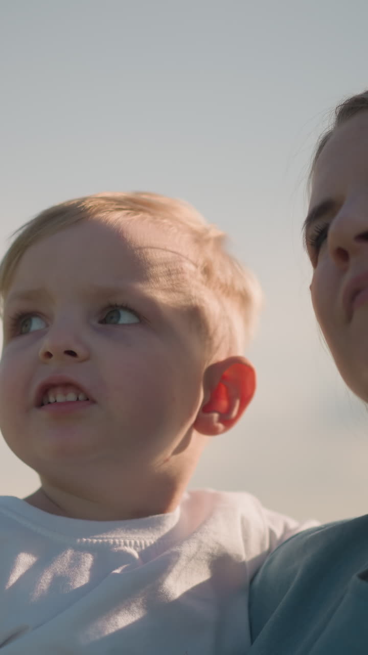 하 을 입은 어린 아들을 들고 있는 파란 드레스를 입은 여자의 클로즈업. 소년은 주변을 주의 깊게 가리키고, 은 날 호기심과 탐험의 순간.