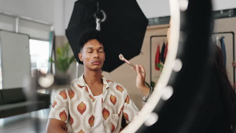 artista de maquillaje aplicando maquillaje a un modelo en un estudio