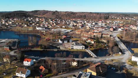 aerial pan shot of small swedish village named bengtsfors with lake and hills in background during beautiful weather outdoors