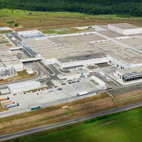 industrial plant in green nature. large area of contemporary factory with many trucks and parking places. harmful manufacture in environment. aerial view