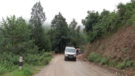 kathmandu, nepal - september 27, 2019: traffic and vehicles on a dangerous, muddy mountain road in the foothills of kathmandu, nepal on september 27, 2019.