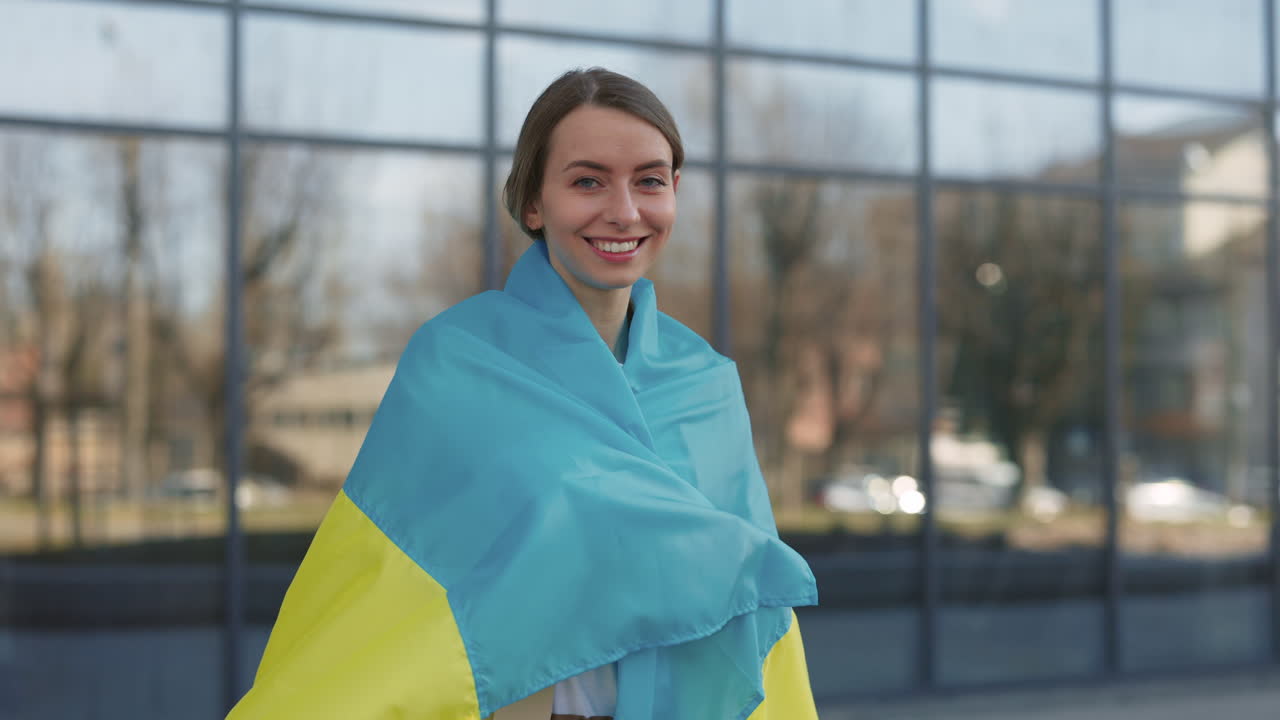 Young Woman Wrapped in Ukrainian Flag Smiling Outdoors
