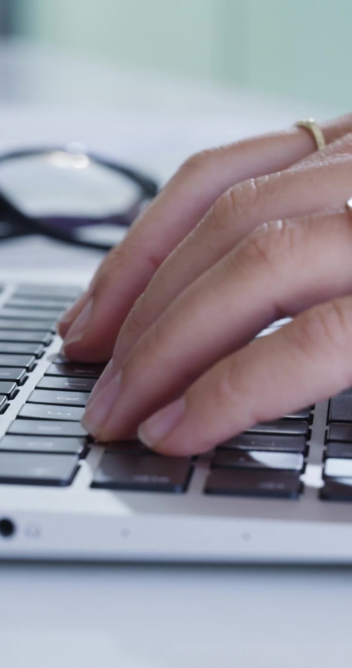 Primo piano di una persona che digita sulla tastiera del laptop in ufficio