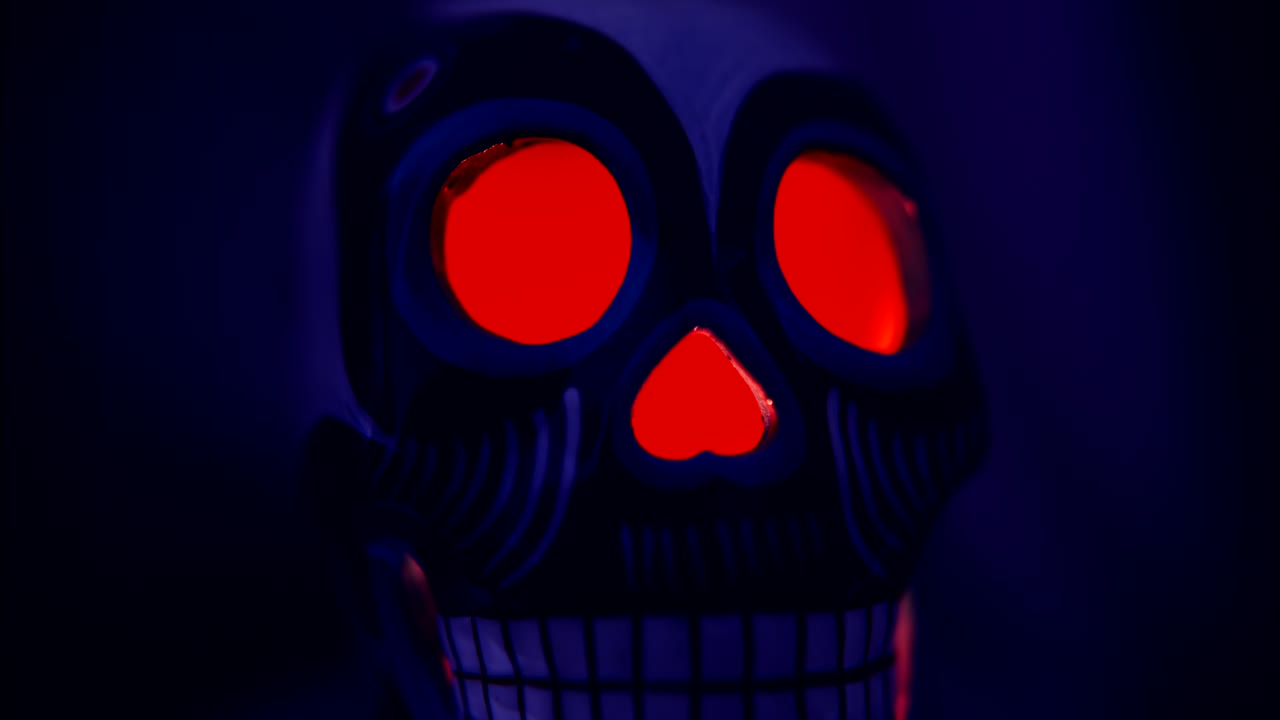 Teschio Calavera con occhi rossi luminosi, rivelato nella luce blu scura