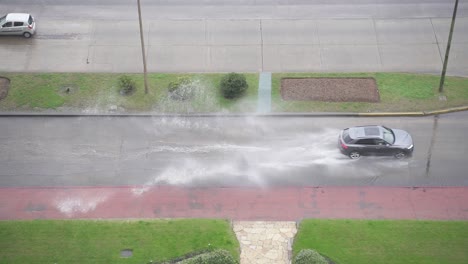 Top-Down-View-Of-Car-Driving-By-Flooded-Street,-Punta-Del-Este,-Uruguay