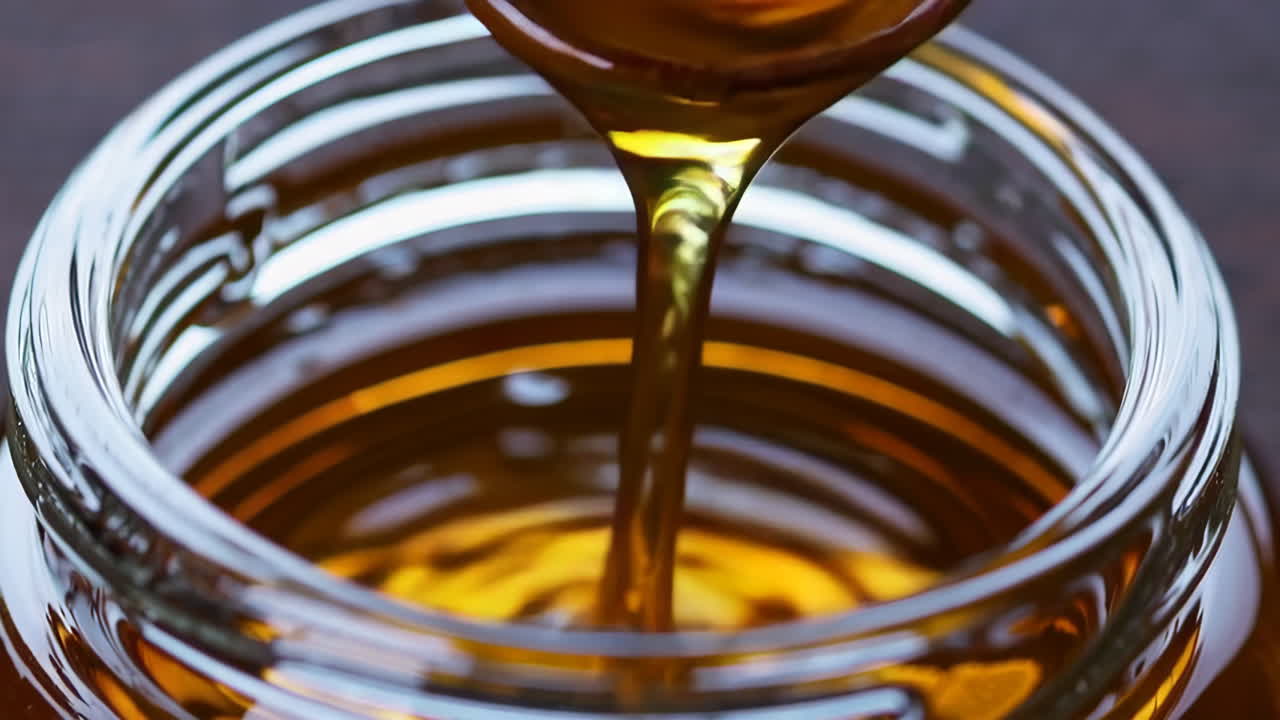 Miele che si versa in un barattolo di vetro