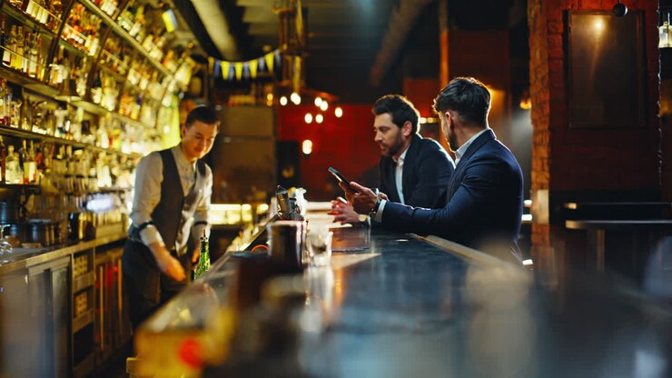 Uomo solo seduto al bancone di un bar con un cocktail. Uomo in abito elegante che incontra un amico