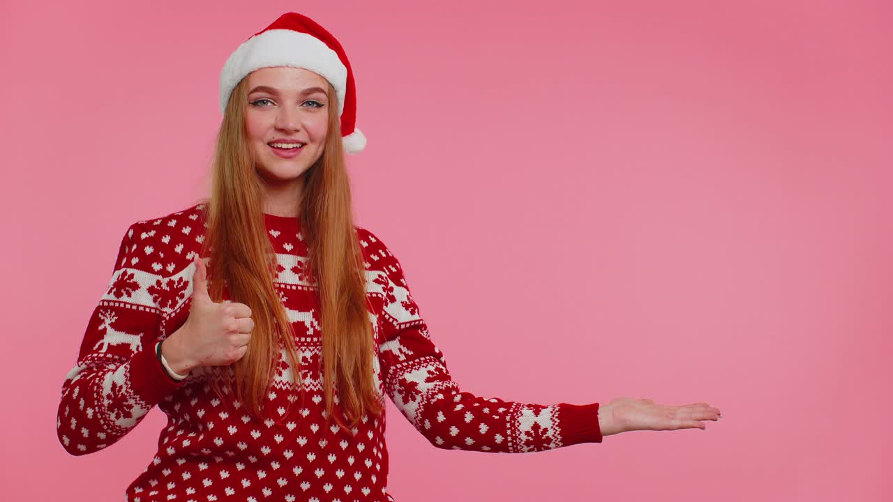 mujer lleva suéter de año nuevo rojo ciervo mostrando los pulgares hacia arriba y señalando en el espacio de publicidad en blanco