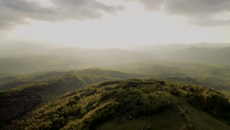 aerial view of rolling green mountains and forests with hazy sunlight