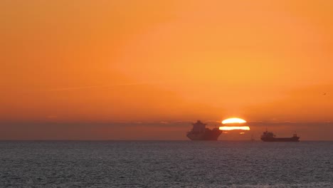 beautiful evening sunset with big sun and some boats on atlantic ocean