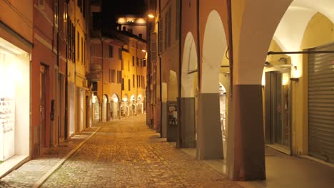 shot of empty historic street near main square due to covid restrictions at night in cesena, northern italy
