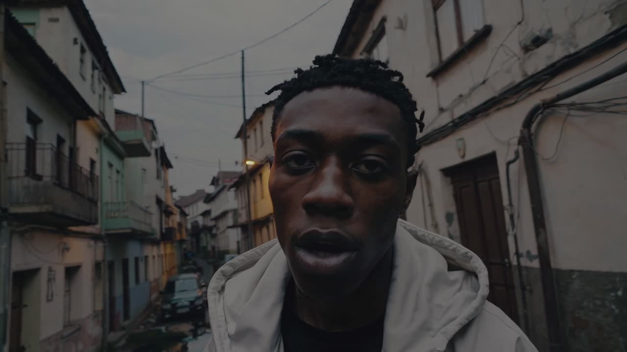 Young African American male passionately performing rap music with urban background, capturing authentic street culture and emotional artistic expression in challenging neighborhood environment