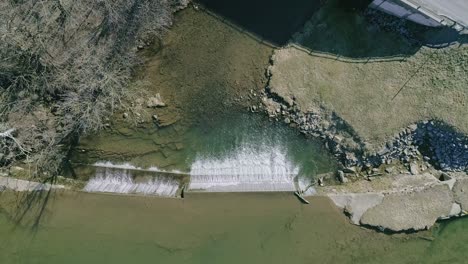 an aerial downward view of a man made waterfall for a mill, on a sunny day