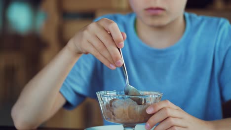 boy is eating ice cream in a cafe. kid with sundae