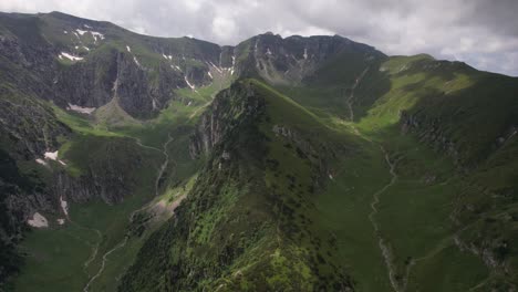 lush green valleys nestled between the rugged peaks of the bucegi mountains, under cloudy skies