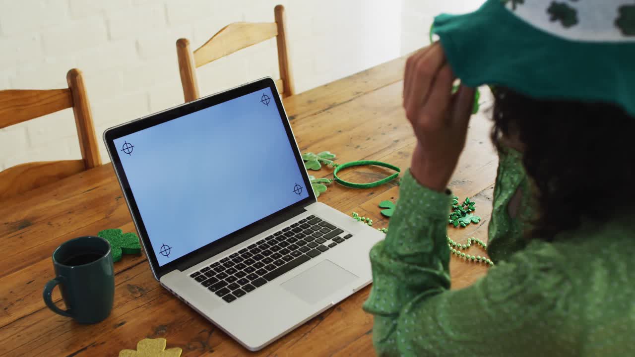 mujer de raza mixta con gafas verdes y disfraz haciendo una videollamada en una computadora portátil en casa