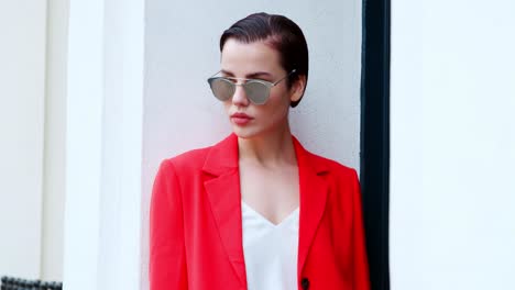 stylish woman wearing sunglasses standing outside city building