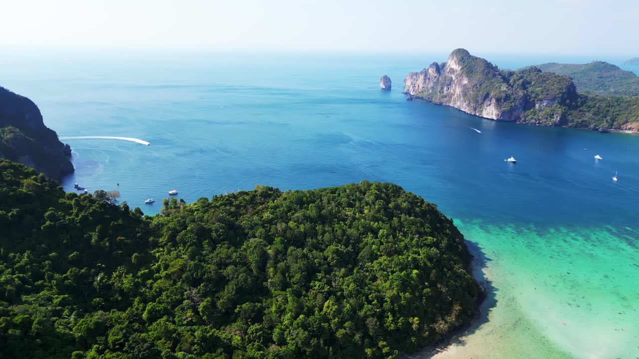 Acqua turchese che circonda un'isola tropicale con vegetazione verde lussureggiante in Thailandia.