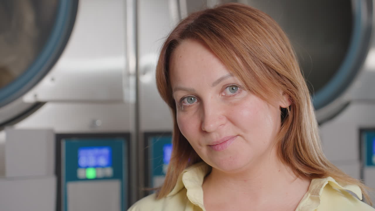 Portrait of staff standing before industrial dryer, washer inside modern laundromat, stainless drums gleaming, digital panels glowing, service pride, cleanliness focus, friendly confident expression