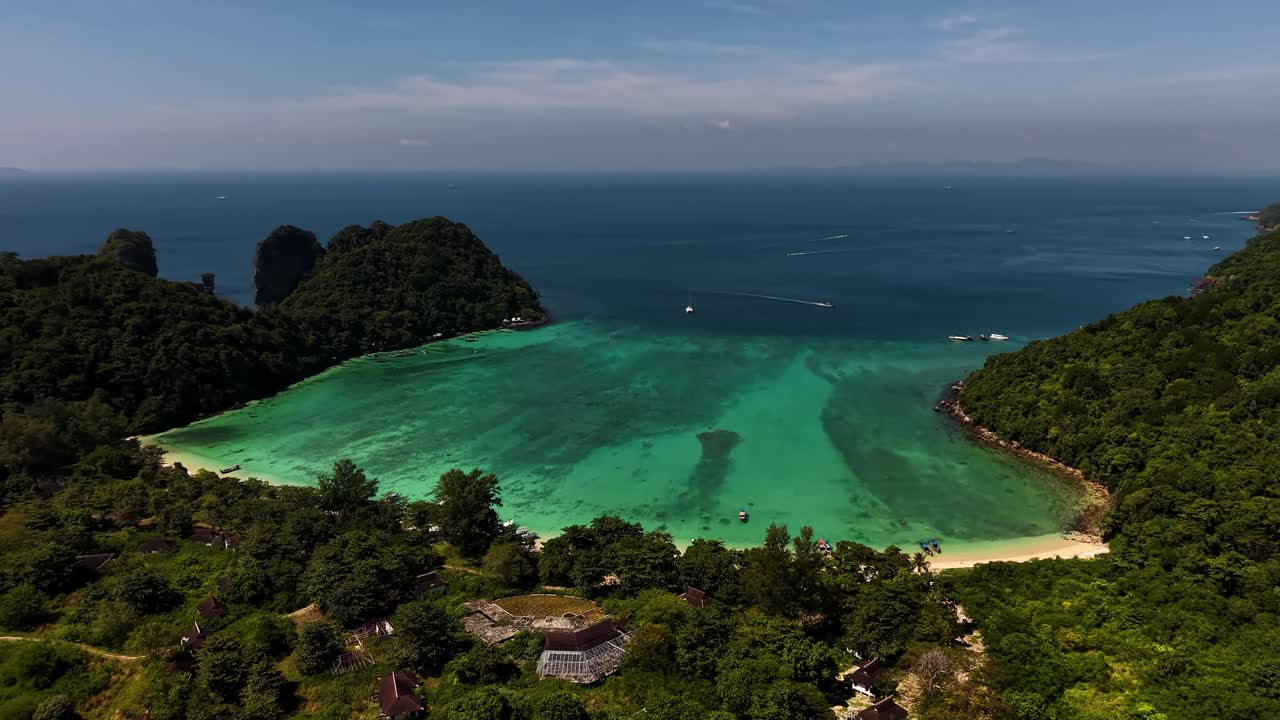 Cảnh quay tổng thể một vịnh nhiệt đới rộng lớn bên cạnh những dãy núi đá vôi khổng lồ và rừng xanh rậm rạp.