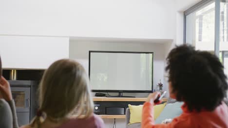 diverse teenager girls friends eating popcorn and watching tv at home, slow motion