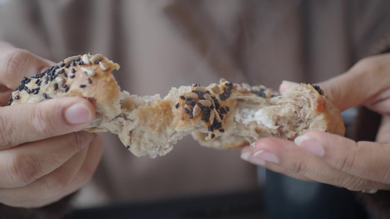 Person Breaking Open a Warm Freshly Baked Seeded Bread Roll