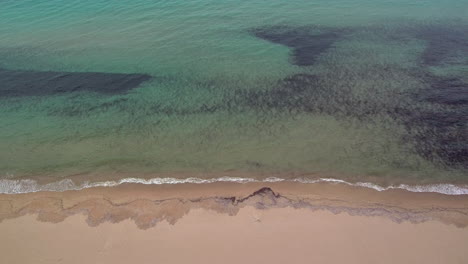 medium sideways flight right above sand at kalogria beach with view of ocean spotted dark bottom, greece, aerial