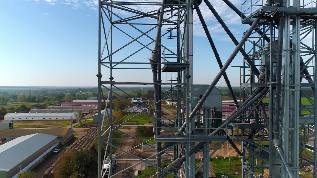 Steel frame in the industrial territory. Industrial plant in farmland. Grain elevators and metal equipment of a factory. View from above.