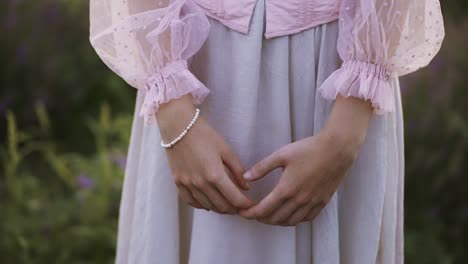 shy woman in beautiful pink dress, close-up of hand